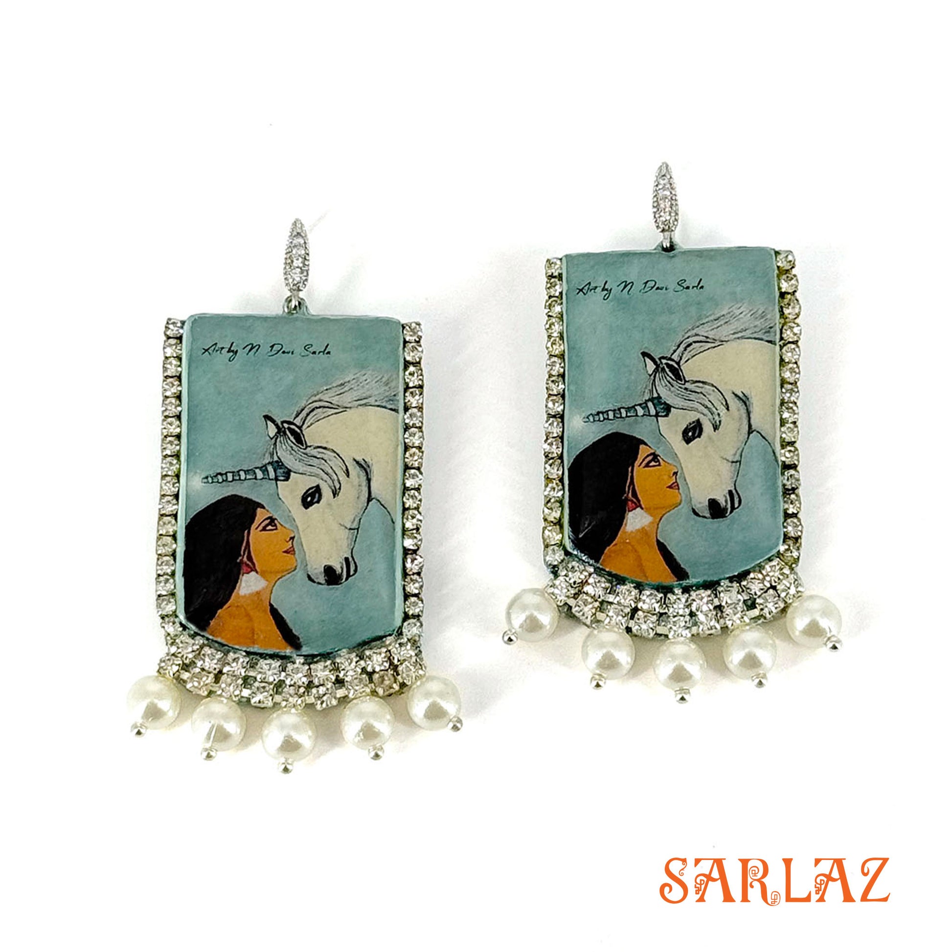 Earrings with artistic depiction of a woman and a unicorn on a blue background, featuring the brand 'SARLAZ'.