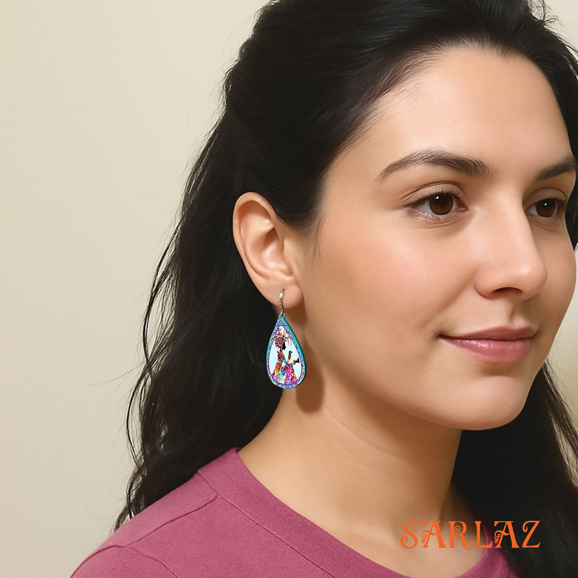 Woman wearing a colorful earring with a neutral background, featuring the brand 'SARLAZ'.