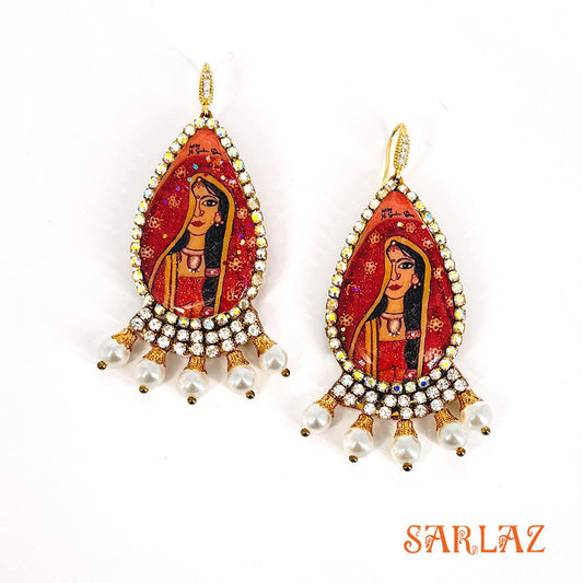 Decorative earrings with a portrait of an Indian bride design, featuring the brand 'SARLAZ'.