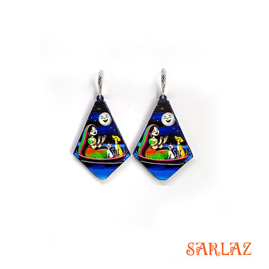Pair of diamond-shaped earrings with colourful art of a girl, with her cat and dog sitting on a boat, under the moonlit, featuring the brand 'SARLAZ'.