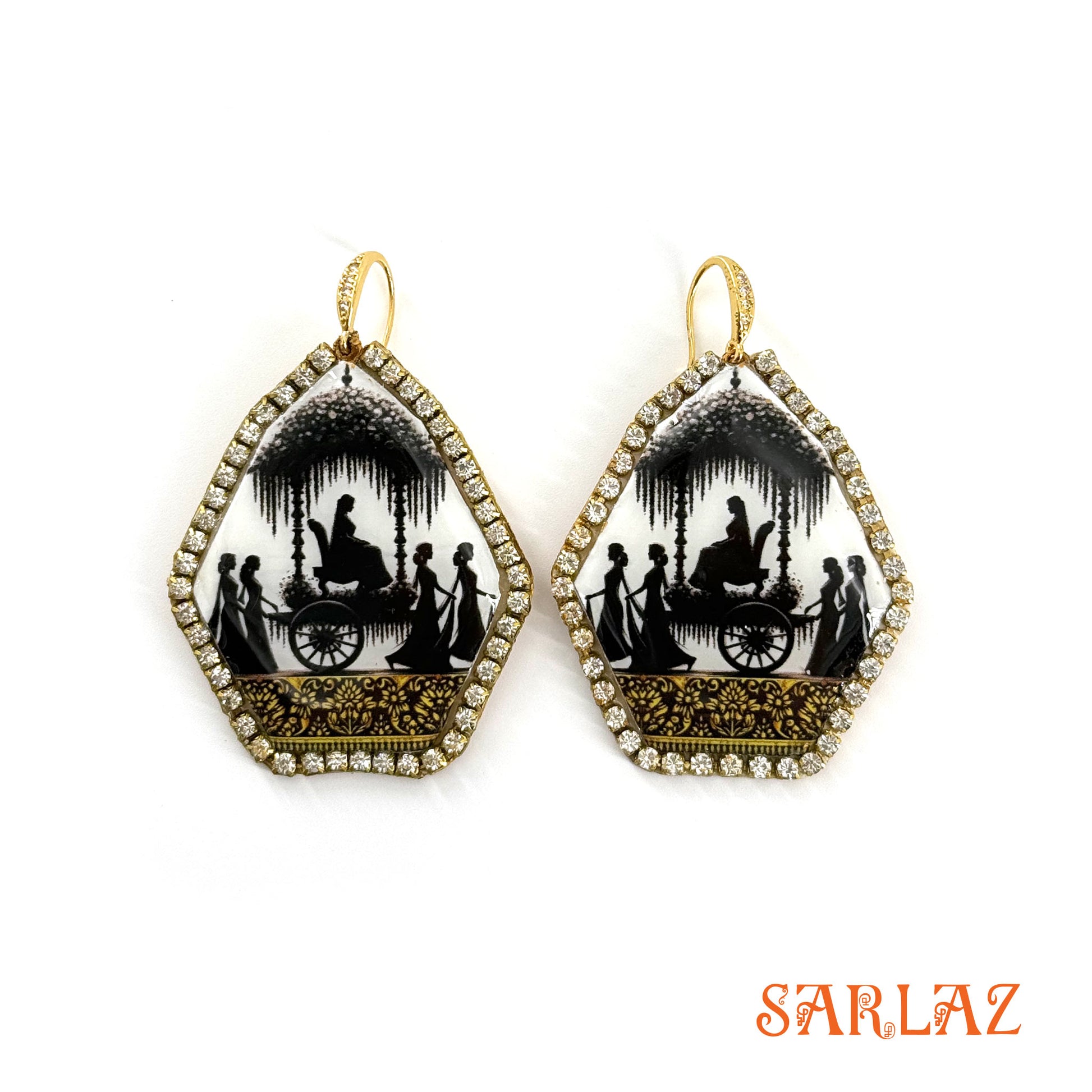 Pair of earrings with black and white silhouettes of Bride going in a convoy in a gold accents on a white background, featuring the brand 'SARLAZ'.