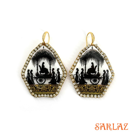 Pair of earrings with black and white silhouettes of Bride going in a convoy in a gold accents on a white background, featuring the brand 'SARLAZ'.