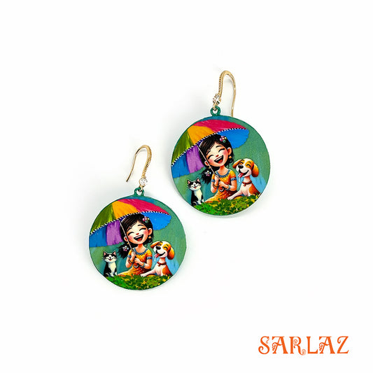 Hand-painted on wood in a circular shape, this vibrant design captures a girl laughing with her dog and cat under a colourful umbrella, featuring the brand 'SARLAZ'.
