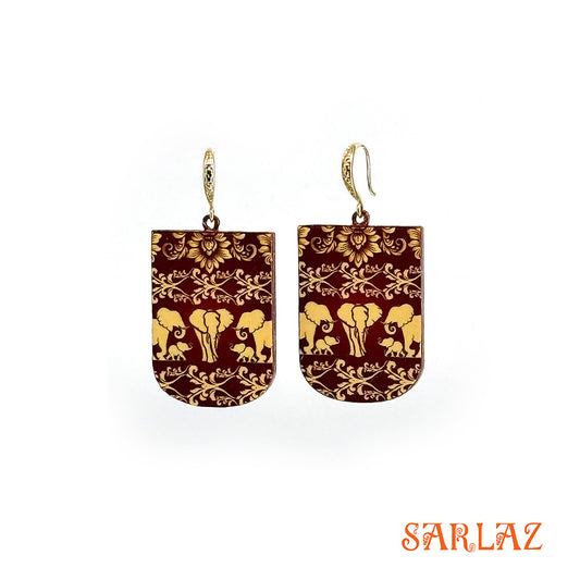 Pair of earrings with gold elephant design on a brown background, branded 'SARLAZ'.