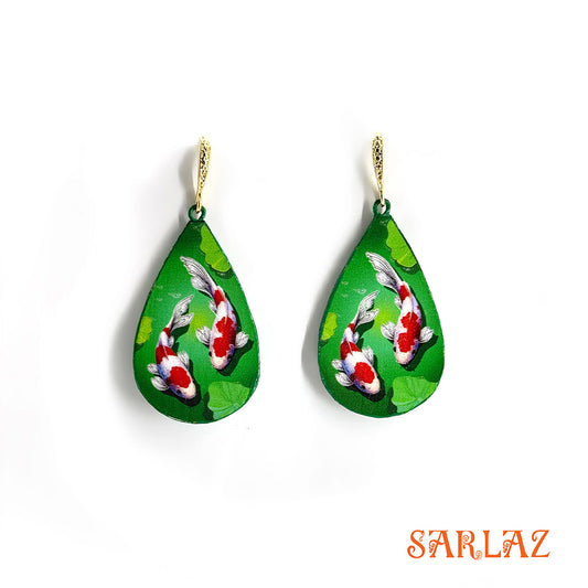 Teardrop-shaped earrings with koi fish design on a green background, brand 'SARLAZ' visible.