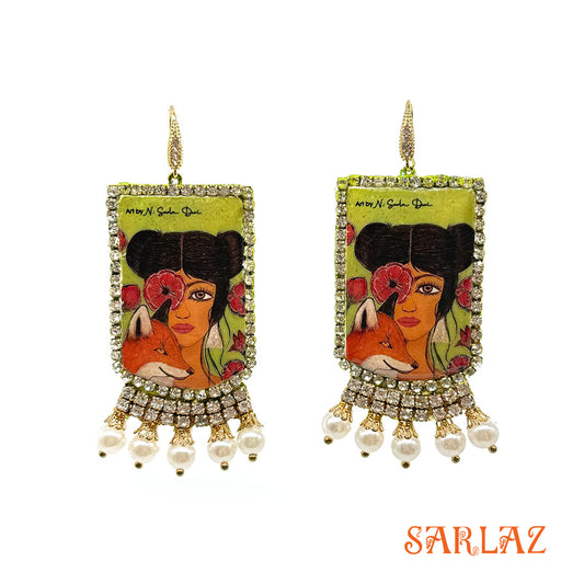Pair of earrings of a Fox and woman with artistic design and pearl embellishments on a white background, featuring the brand 'SARLAZ'.