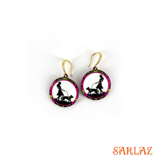Pair of earrings with a design of a woman walking a dog on a white background, branded with SARLAZ.