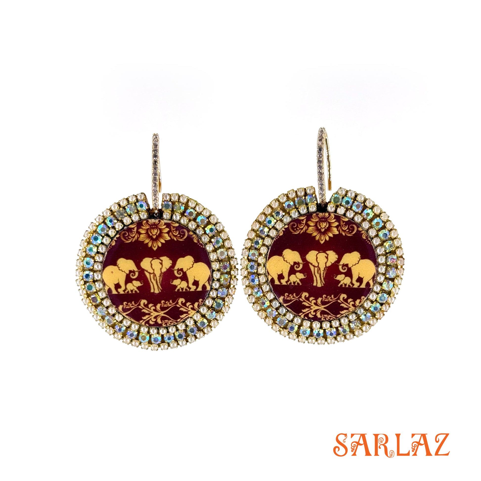 Pair of earrings with elephant family design on maroon pattern background, featuring the brand 'SARLAZ'.