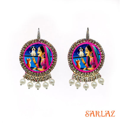Decorative earrings with a colorful design featuring a woman, dog, and cat, branded 'SARLAZ'.